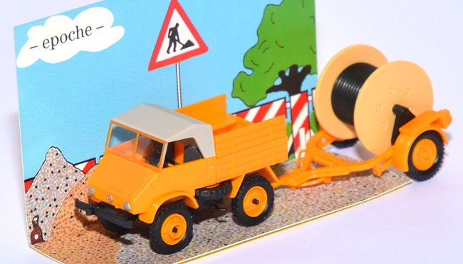 Mercedes-​Benz Unimog 411 mit Kabellege-​Anhänger orange